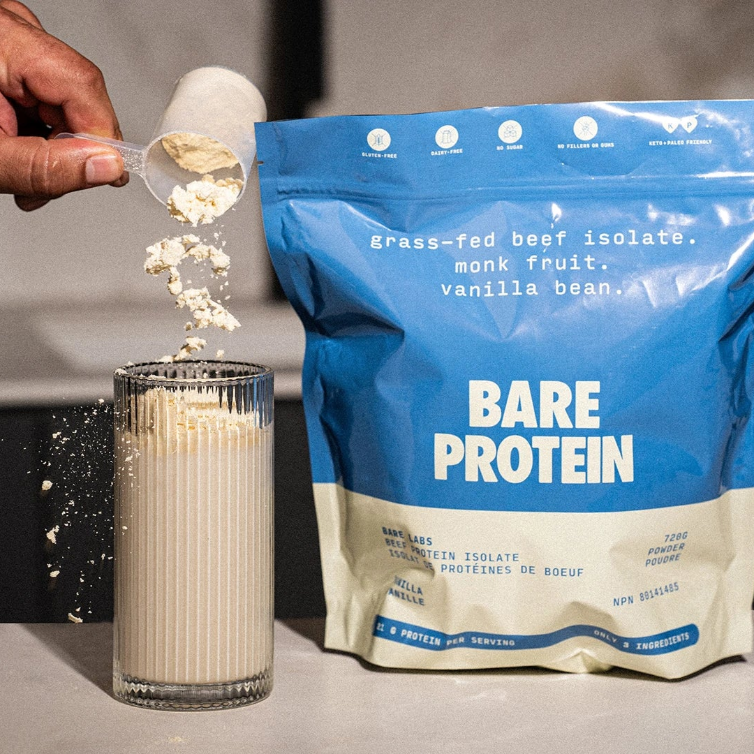 Person pouring Bare Protein into a glass on a kitchen counter